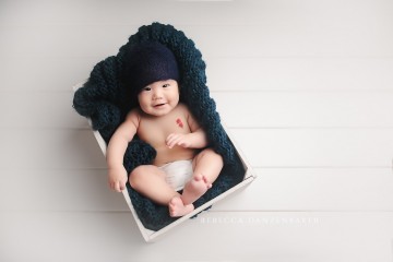 Baby boy smiling sitting in a white box in baby photography studio in Northern VA