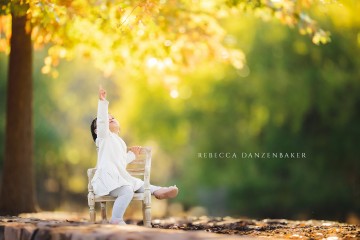 One year old girl portrait sitting under a tree in the fall pointing at the leaves