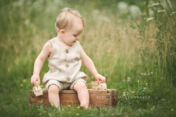Baby boy playing with wooden truck during baby photography session