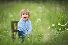 Baby boy sitting outside on a wooden chair in a flower field Baby boy sitting outside on a wooden chair in a flower field