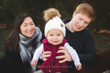 Baby girl smiling at the camera while being held by her parents