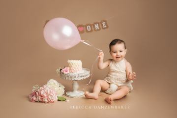 Girl with balloon cake smash for first birthday