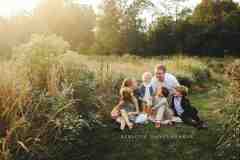 Family sitting in a wildflower field in Willowsford for a family portrait Family sitting in a wildflower field in Willowsford for a family portrait