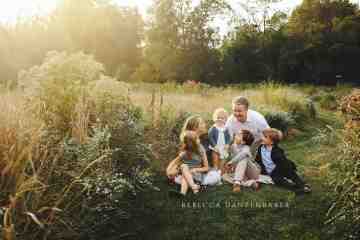 Family sitting in a wildflower field in Willowsford for a family portrait