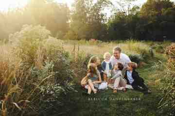 Family sitting in a wildflower field in Willowsford for a family portrait Family sitting in a wildflower field in Willowsford for a family portrait
