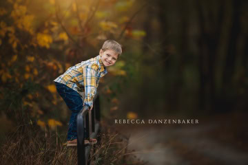 portrait of boy climbing a fence in the fall