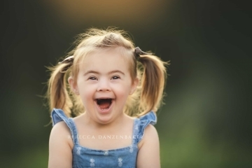 Girl with Down Syndrome smiling during a photo session with Rebecca Danzenbaker