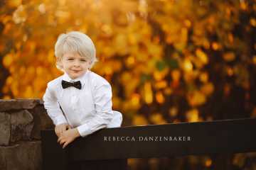 bowtie boy on fence with yellow leaves around him