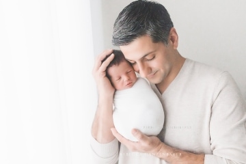 Father snuggling newborn baby