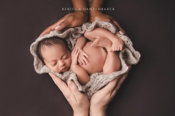 Newborn Baby being cradled in both parents' hands