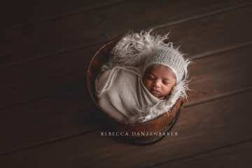 Newborn baby sleeping in a bucket prop