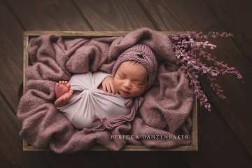 Newborn girl sleeping in purple props