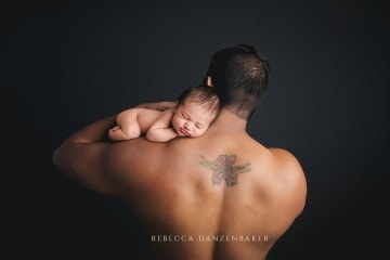 Newborn baby with dad and his Iris back tattoo