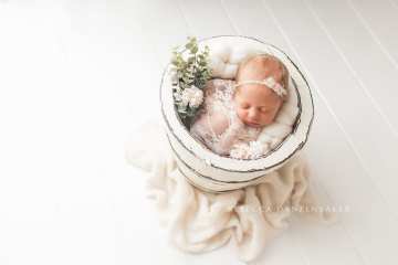 Newborn baby with flowers in bucket