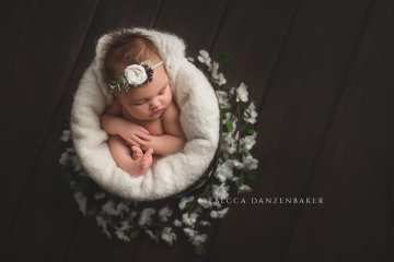 Sleeping newborn girl in bucket with flowers