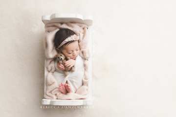 Sleeping newborn baby girl in a white bed