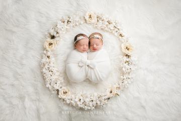Twin newborn babies surrounded by flowers