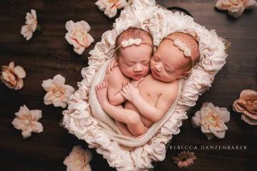 Newborn twin girls with pink flowers