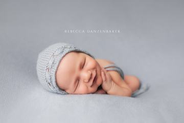 Smiling newborn baby on light blue blanket